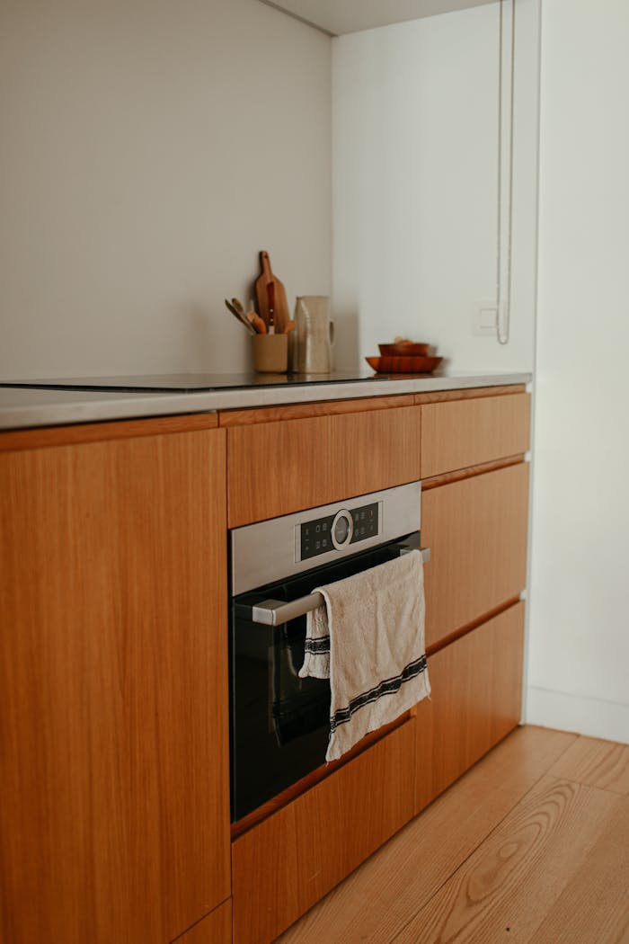 Modern minimalist kitchen featuring wooden cabinets and built-in oven.
